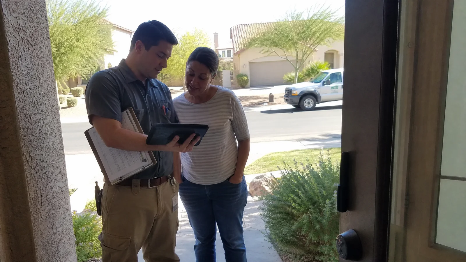 Pest control technician reviewing a recurring service schedule at a Phoenix front door